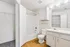 Bright and modern bathroom with sleek white cabinetry, elegant fixtures, and a spacious walk-in closet.