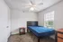 Bright and cozy bedroom featuring a sleek bed frame, large window with abundant natural light, and modern ceiling fan.