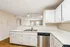 Modern kitchen with sleek white cabinetry, spacious countertops, and stainless steel appliances offering an inviting open-concept layout.