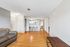 Inviting open-plan living space featuring sleek hardwood flooring, a cozy sofa, and a modern kitchen with barstools.