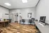 Bright and modern home office space featuring elegant wood tile floors, sleek workstations with ergonomic chairs, and ample natural light.