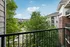Charming balcony view showcasing lush greenery and modern apartment buildings under a bright blue sky.