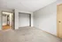 Spacious bedroom with soft carpet flooring, open closet, and direct access to a modern bathroom with hardwood floors.