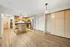 Contemporary open kitchen with stainless steel appliances and wooden cabinetry, complemented by light wood flooring and modern lighting.