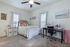 Bright and inviting bedroom with plush carpet, featuring a cozy bed adorned with decorative pillows, a functional desk space for productivity, and charming decor elements under soft natural light.
