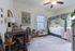 Charming bedroom featuring a cozy canopy bed, elegant desk, and tasteful decor with vibrant plants and artistic wall hangings.