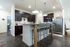 Modern kitchen space with sleek dark cabinets, stainless steel appliances, and a stylish breakfast bar with high chairs, perfect for entertaining.