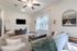 Charming living room boasting a cozy gray sectional, elegant decor, wall-mounted TV, and large window overlooking a serene outdoor view.