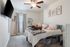 Cozy bedroom with plush carpet, elegant ceiling fan, mounted TV, and charming decor, perfect for relaxation.