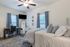 Inviting bedroom with serene decor, plush bedding, and a cozy workspace under soft natural light.