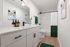 Bright, modern bathroom with elegant white cabinetry, sleek fixtures, and stylish green accents, creating a refreshing ambiance.