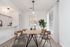 Elegant dining area featuring a modern wooden table with stylish chairs, soft lighting, and vibrant artwork, perfect for entertaining.