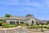 Charming leasing office and fitness center with beautiful landscaping and modern architecture under a clear blue sky.