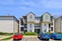 Charming apartment complex with modern architecture, ample parking, and lush landscaping against a clear blue sky.