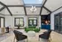 Elegant communal area with a vibrant green sofa, stylish armchairs, and a chic chandelier under a large skylight, creating a welcoming atmosphere.