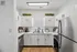 Bright and modern kitchen with sleek white cabinets, stainless steel appliances, and natural light from a large window.