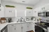 Bright, modern kitchen with sleek white cabinetry, stainless steel appliances, and decorative greenery enhancing a clean, elegant vibe.