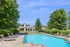 Inviting poolside view with sun loungers and shaded seating area set against a lush garden backdrop, perfect for relaxation and outdoor enjoyment.