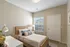 Inviting bedroom with a cozy bed, natural light from a large window, and charming decor creating a warm and welcoming atmosphere.
