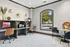 Bright and modern workspace featuring sleek computer stations, stylish chairs, and elegant decor with a large window overlooking a lush green outdoor view.