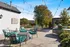 Charming outdoor patio adorned with string lights, featuring cozy teal cushioned seating, a modern fire pit, and a lush garden backdrop.