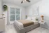Bright and elegant bedroom with large window, plush bed, and modern decor.