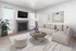 Inviting living room with a modern fireplace, plush beige sofa, and elegant decor, bathed in natural light from large windows.