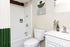 Modern bathroom featuring elegant white fixtures, a stylish green and white shower curtain, and chic decor accents for a fresh and inviting atmosphere.
