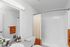 Elegant bathroom with modern fixtures, featuring a sleek white sink, soft lighting, and chic orange accents.