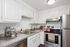 Modern kitchen with sleek white cabinets, stainless steel appliances, and a cozy coffee station.