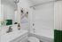 Modern bathroom featuring sleek white fixtures, elegant wall art, and a stylish shower curtain in green and white.