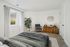 Bright, modern bedroom with cozy bedding, elegant decor, and a lush plant creating a peaceful retreat.