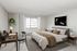 Elegant bedroom featuring a plush bed with neutral bedding, chic desk area, and a large window flooding the room with natural light.