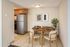 Inviting dining area with a stylish wooden table, modern chairs, and elegant decor, adjacent to a well-appointed kitchen with wooden cabinetry.