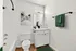 Bright, modern bathroom with sleek white vanity, elegant artwork, and cozy green accents.