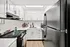 Modern kitchen with sleek white cabinets, black appliances, and stylish wood flooring, offering a bright and inviting cooking space.