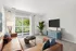 Inviting living room with a cozy brown sofa, stylish decor, and a large window offering lush greenery views.