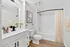 Elegant bathroom featuring sleek white cabinets, contemporary fixtures, and warm wood flooring, perfect for a serene oasis.