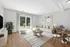 Bright and inviting living room with modern decor, featuring a cozy sectional sofa, stylish rug, and elegant dining area with garden views.
