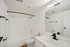 Sleek modern bathroom with elegant fixtures, featuring a pristine white bathtub, contemporary sink, and ample natural light.