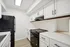 Sleek modern kitchen featuring white cabinetry, stainless steel appliances, and elegant wood flooring with abundant natural light.