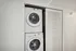 Compact laundry area with modern stacked washer and dryer behind sleek sliding doors, optimizing space efficiently.