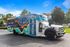 Vibrant and inviting community shuttle bus parked outdoors, featuring eye-catching graphics promoting student living in Tallahassee.