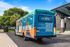 Vibrant reNEW Tallahassee bus showcasing student living redefined, parked in a scenic area with lush greenery and modern architecture.
