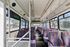 Spacious and vibrant interior of a bus with colorful patterned seats, offering ample seating and bright natural light through large windows.