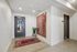 Modern apartment hallway with elegant wall art, vibrant red rug, and a stylish potted plant for a welcoming entrance.
