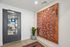 Chic apartment entrance featuring a modern door, vibrant abstract wall art, and a lush potted plant, creating an inviting and stylish ambiance.