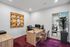 Modern home office with stylish wooden desk, vibrant artwork, and plush chairs on a rich maroon carpet, perfect for productivity.