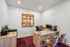 Chic home office with vibrant artwork, stylish desk, and elegant seating on plush carpet.