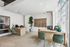 Modern apartment office featuring stylish wood desks, chic green chairs, and large windows for natural light.